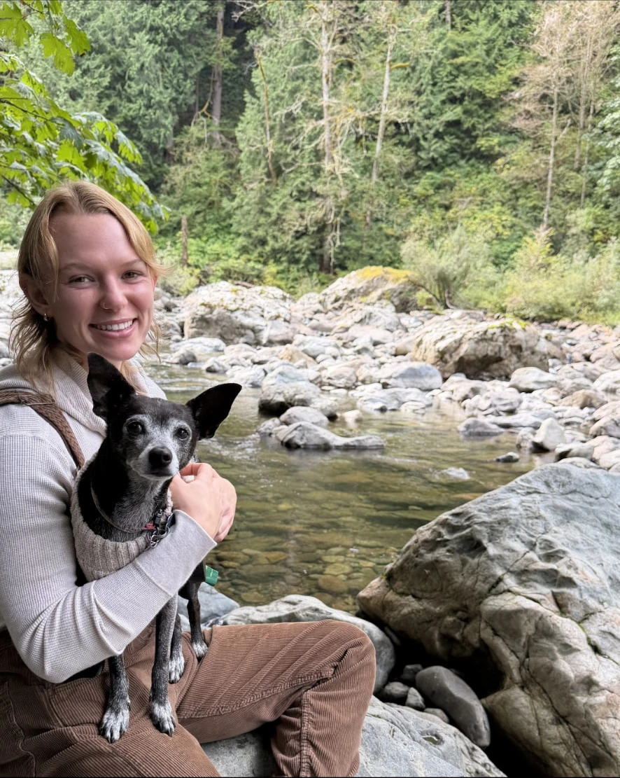 Sky holding Bella beside a rocky forest river