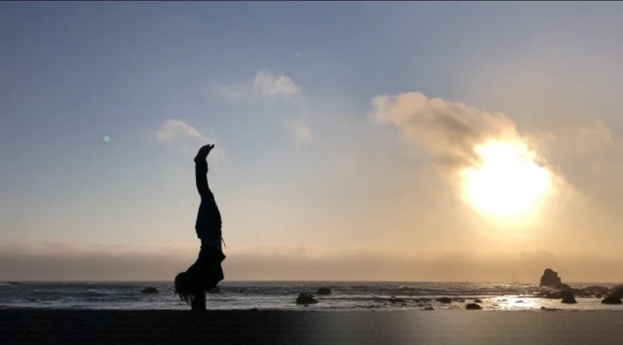 An ocean-sunset handstand on the rocky coast
